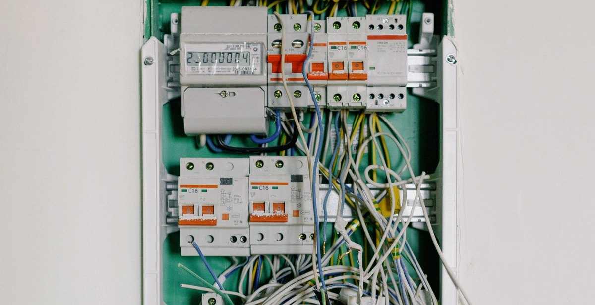 Opened distribution board with untidy wiring, circuit breakers and meter
