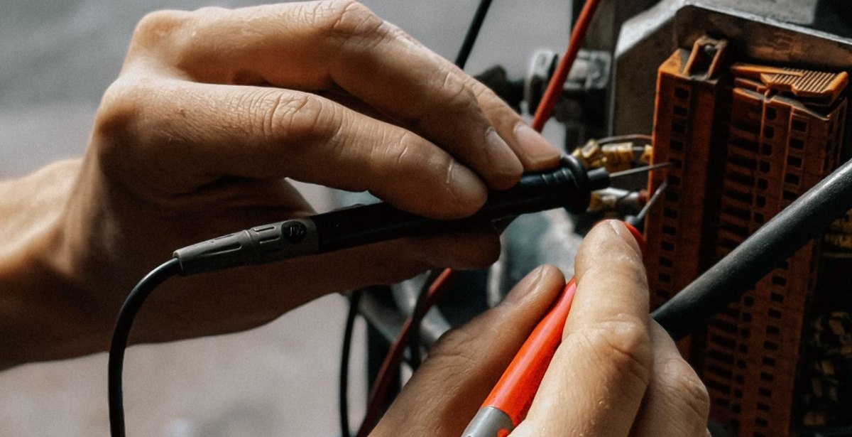 Electrician testing a motor terminal block with multimeter probes